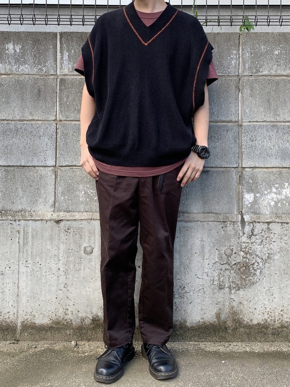 ブラウン系のTシャツ/カットソー、ブラック系のベスト、ブラウン系のチノパンツを着用したメンズの秋コーディネートの1枚目の写真