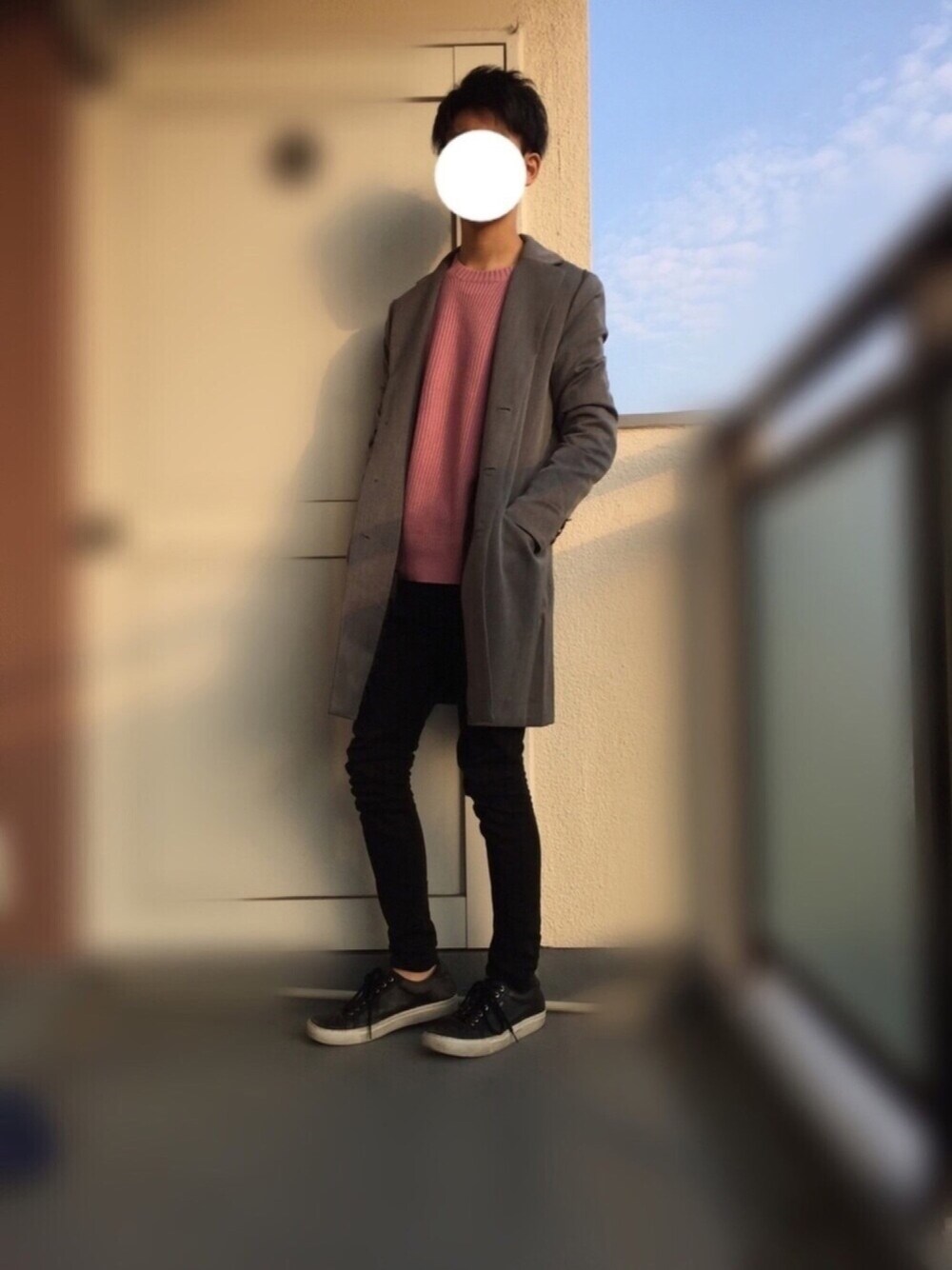 グレー系のチェスターコート、ピンク系のニット/セーター、ブラック系のその他パンツを着用したメンズの春コーディネートの1枚目の写真