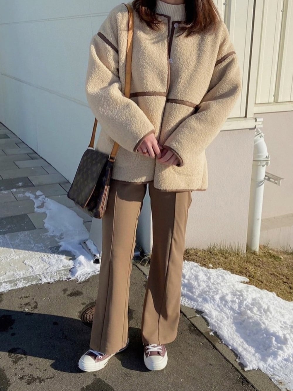 ホワイト系のニット/セーター、ベージュ系のムートンコート、ブラウン系のスニーカーを着用したレディースの冬コーディネートの1枚目の写真