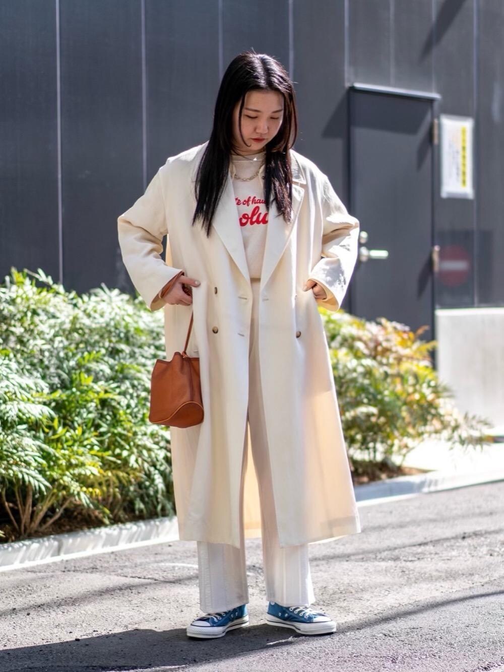 ホワイト系のその他アウター、オレンジ系のハンドバッグ、ブルー系のスニーカーを着用したレディースの春コーディネートの1枚目の写真