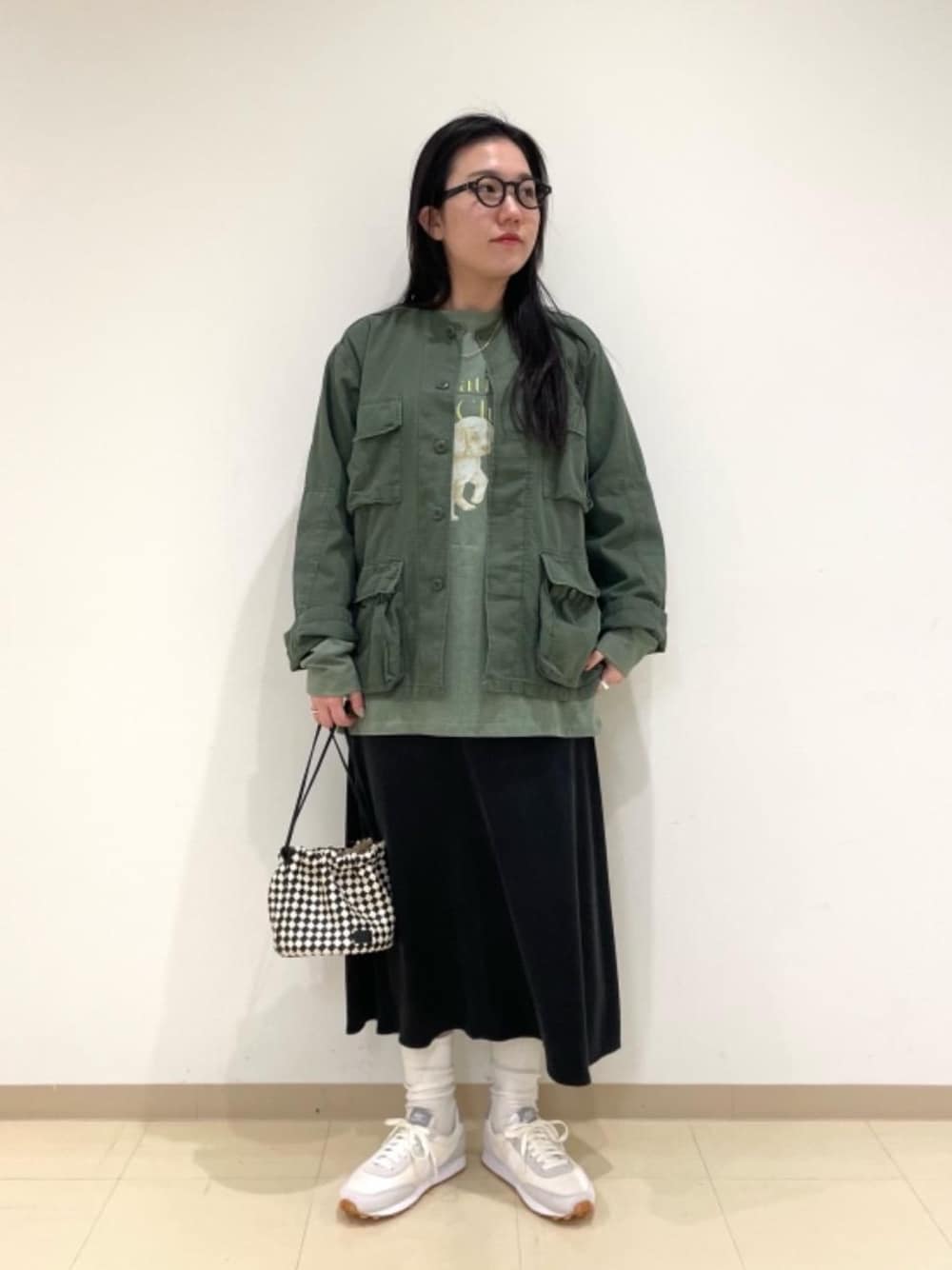 グリーン系のミリタリージャケット、ブラック系のショルダーバッグ、ブラック系のスカートを着用したレディースの冬コーディネートの1枚目の写真