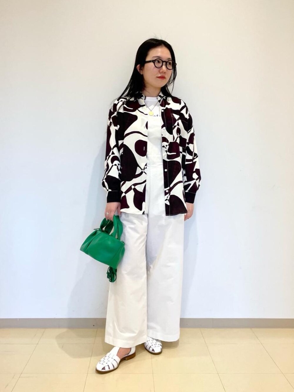 グリーン系のトートバッグ、ホワイト系のサンダル、ホワイト系のTシャツ/カットソーを着用したレディースの冬コーディネートの1枚目の写真