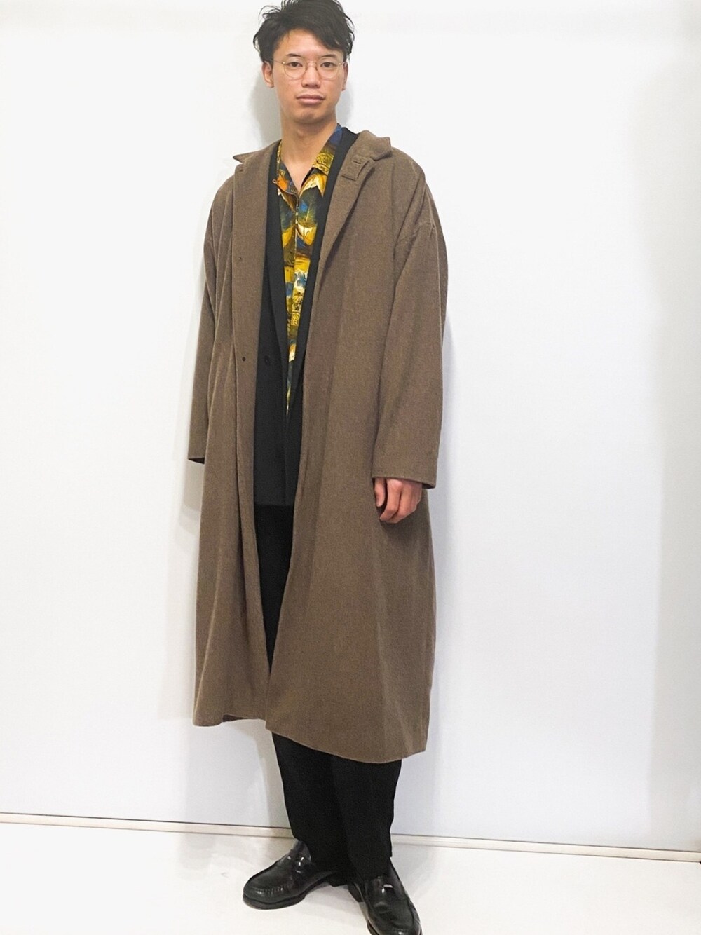 ブラウン系のステンカラーコート、ブラック系のテーラードジャケット、ブラック系のスラックスを着用したメンズの冬コーディネートの1枚目の写真