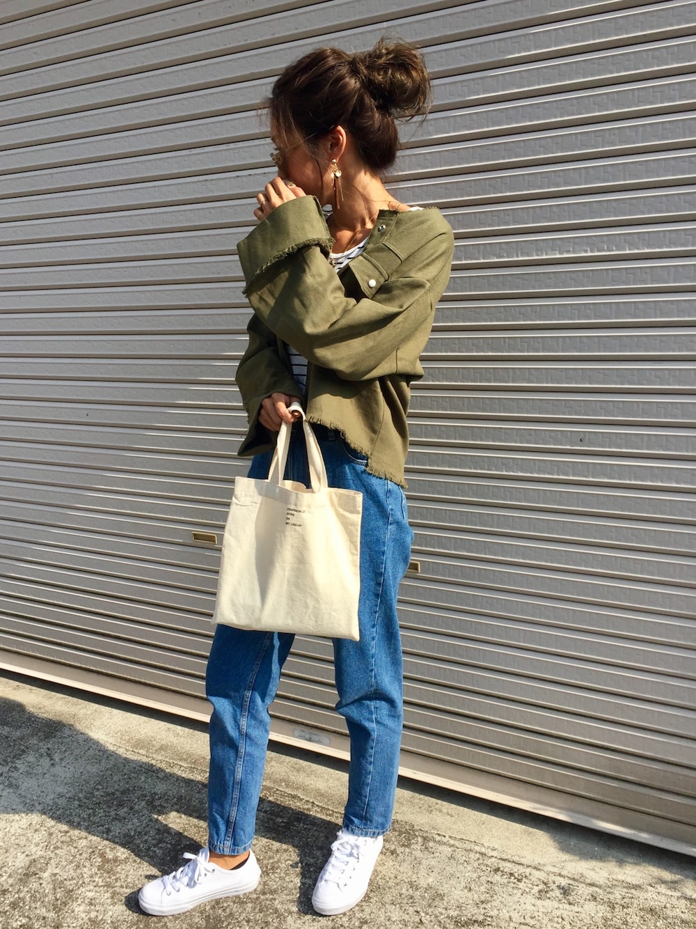 グリーン系のノーカラージャケット、ホワイト系のバッグ、ブルー系のデニムパンツを着用したレディースの夏コーディネートの1枚目の写真