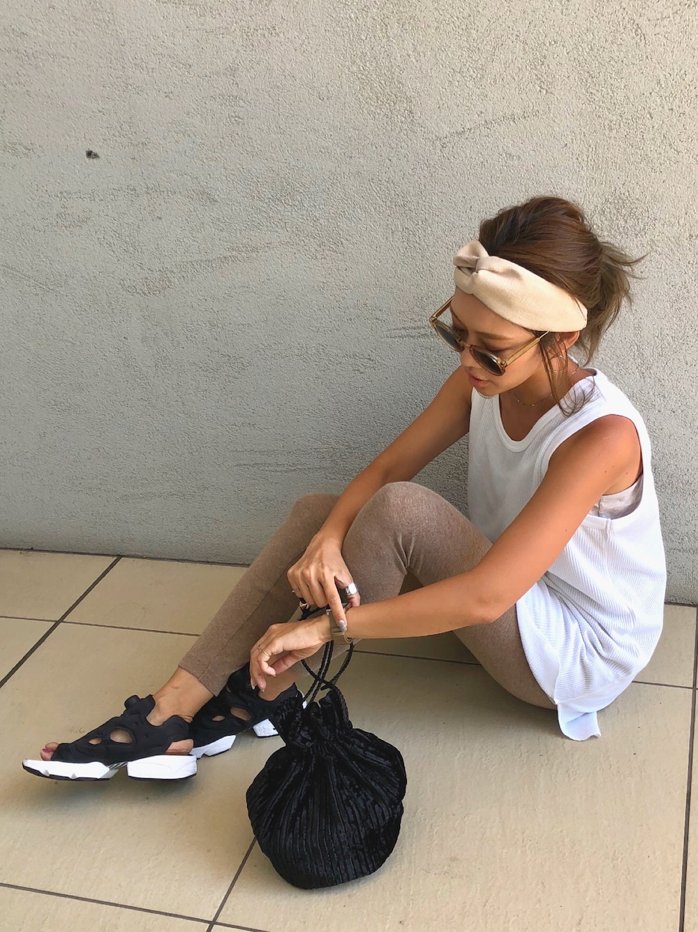 ホワイト系のタンクトップ、ブラック系のサンダル、ブラック系のハンドバッグを着用したレディースの夏コーディネートの1枚目の写真