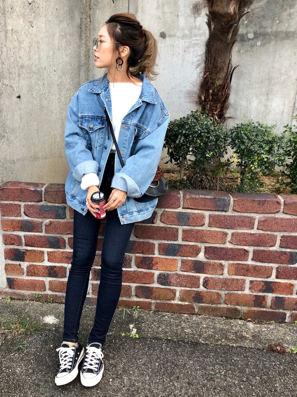 ホワイト系のニット/セーター、ブルー系のデニムパンツ、ブラック系のスニーカーを着用したレディースの秋コーディネートの1枚目の写真