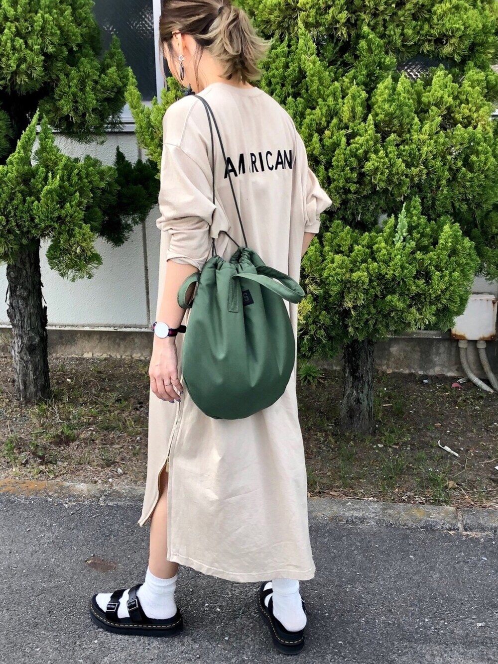 ベージュ系のワンピース、グリーン系のハンドバッグ、ブラック系のサンダルを着用したレディースの春コーディネートの1枚目の写真