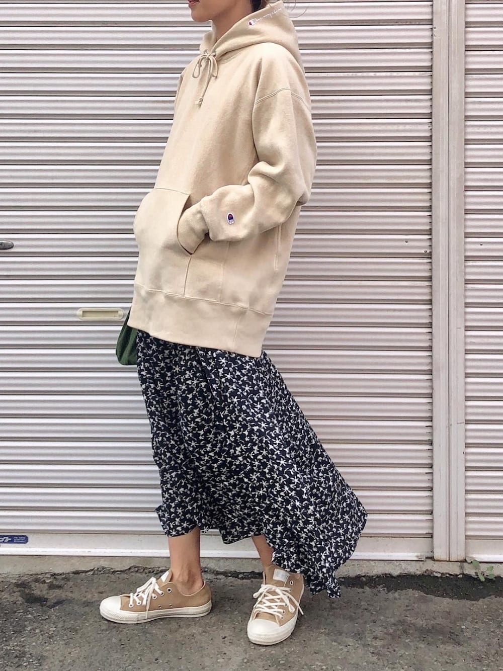 ベージュ系のパーカー、ブラック系のスカート、ベージュ系のスニーカーを着用したレディースの秋コーディネートの1枚目の写真