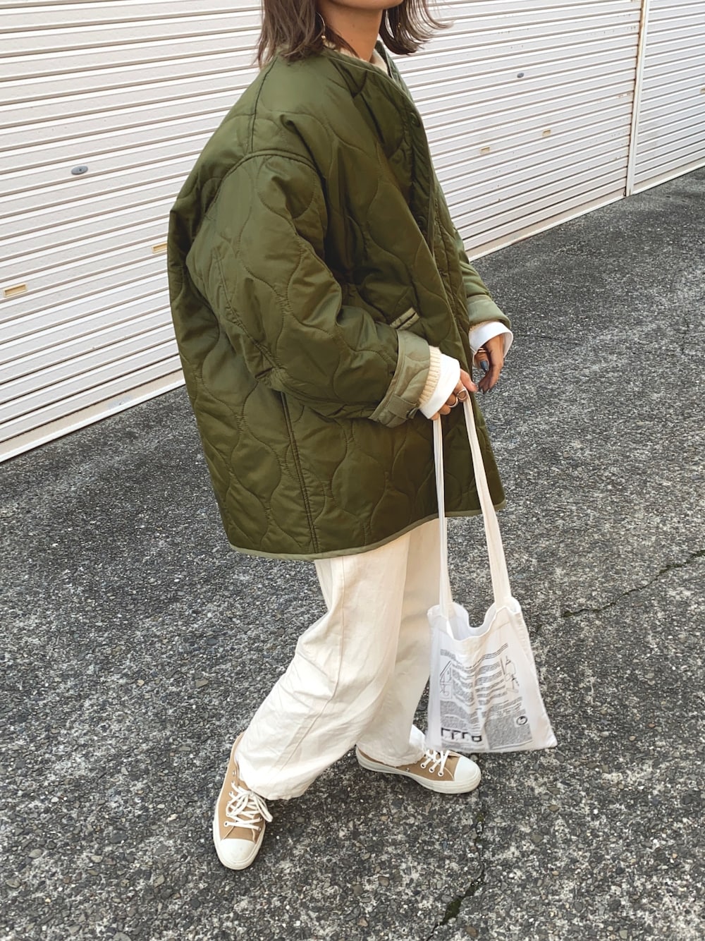 グリーン系のノーカラージャケット、ホワイト系のデニムパンツを着用したレディースの冬コーディネートの1枚目の写真