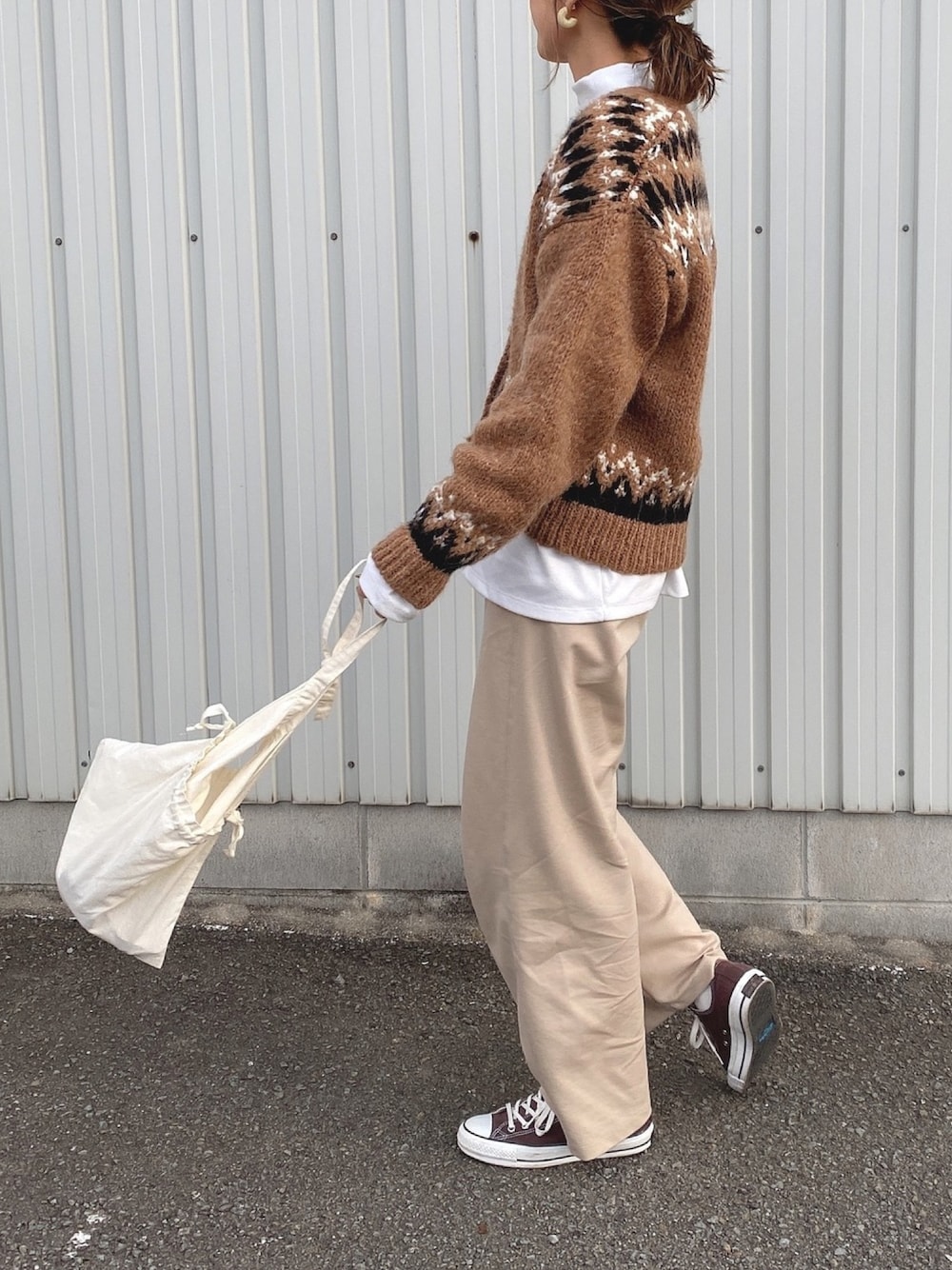 ブラウン系のカーディガン/ボレロ、ブラウン系のスニーカー、ホワイト系のボディバッグ/ウエストポーチを着用したレディースの冬コーディネートの1枚目の写真