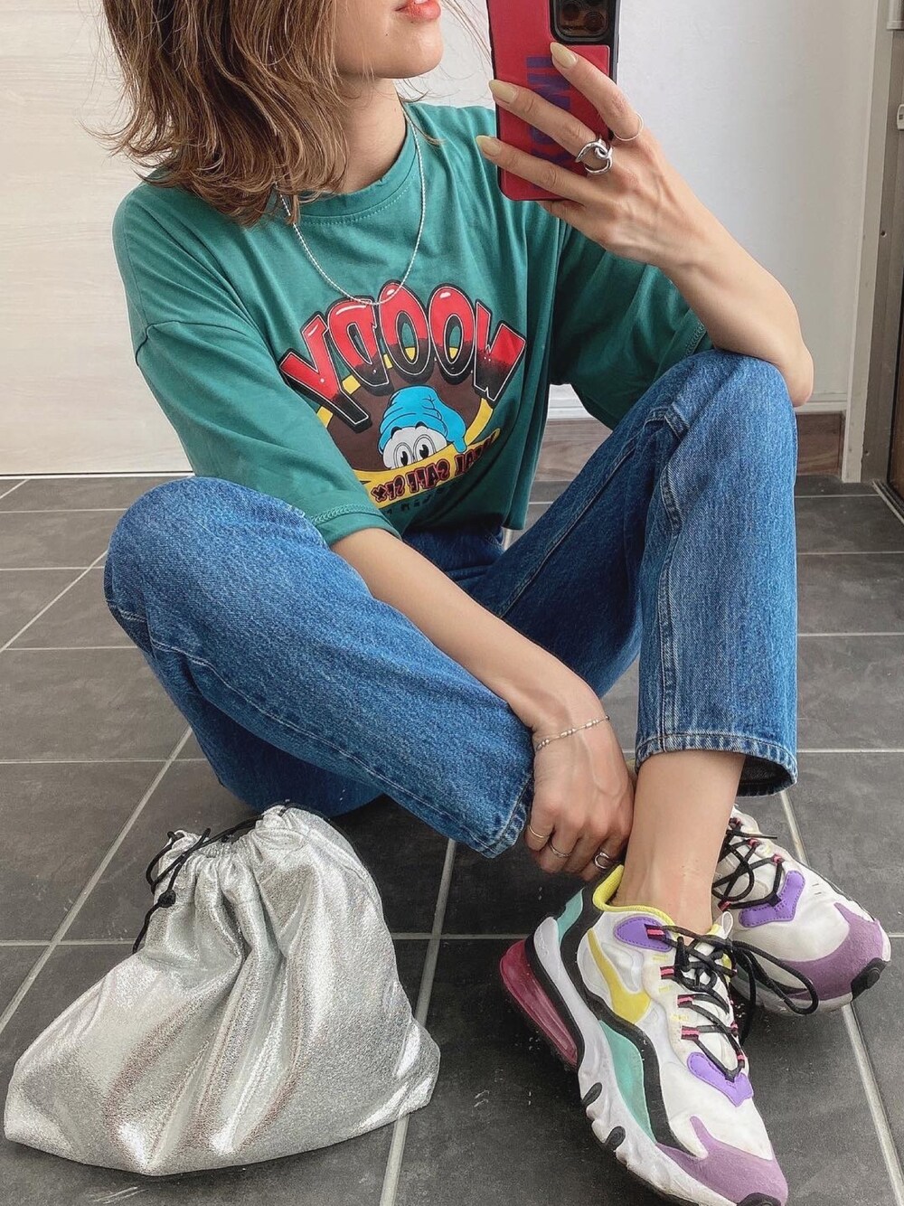 ブルー系のデニムパンツ、シルバー系のショルダーバッグ、ホワイト系のスニーカーを着用したレディースの春コーディネートの1枚目の写真