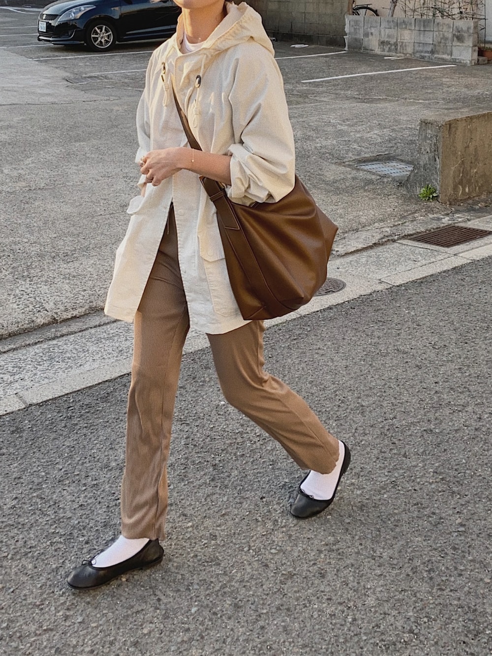 ベージュ系のパンツ、ホワイト系のパーカー、ブラウン系のショルダーバッグを着用したレディースの春コーディネートの1枚目の写真