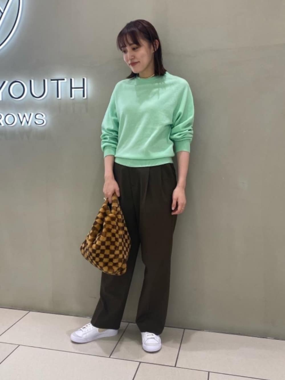 ブラウン系のショルダーバッグ、ホワイト系のスニーカー、グリーン系のその他パンツを着用したレディースの秋コーディネートの1枚目の写真