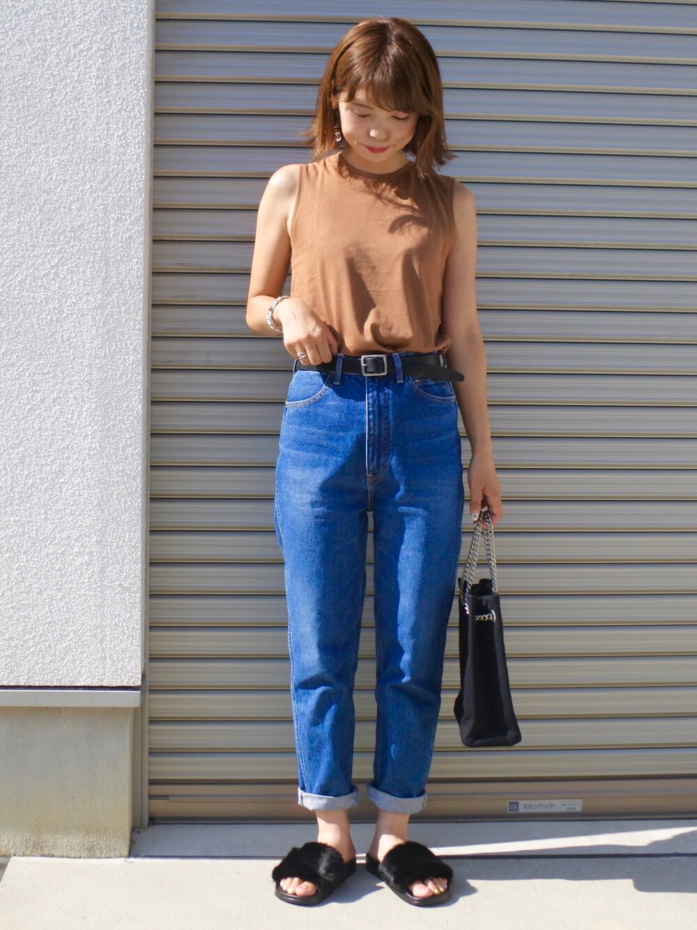 ベージュ系のタンクトップ、ブルー系のデニムパンツ、ブラック系のショルダーバッグを着用したレディースの夏コーディネートの1枚目の写真