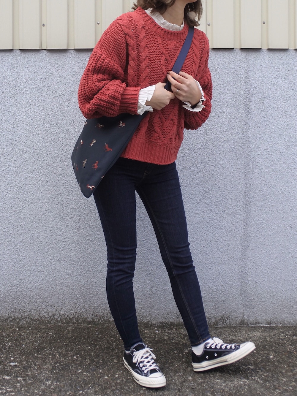 オレンジ系のニット/セーター、ブルー系のショルダーバッグ、ベージュ系のピアス（両耳用）を着用したレディースの冬コーディネートの1枚目の写真