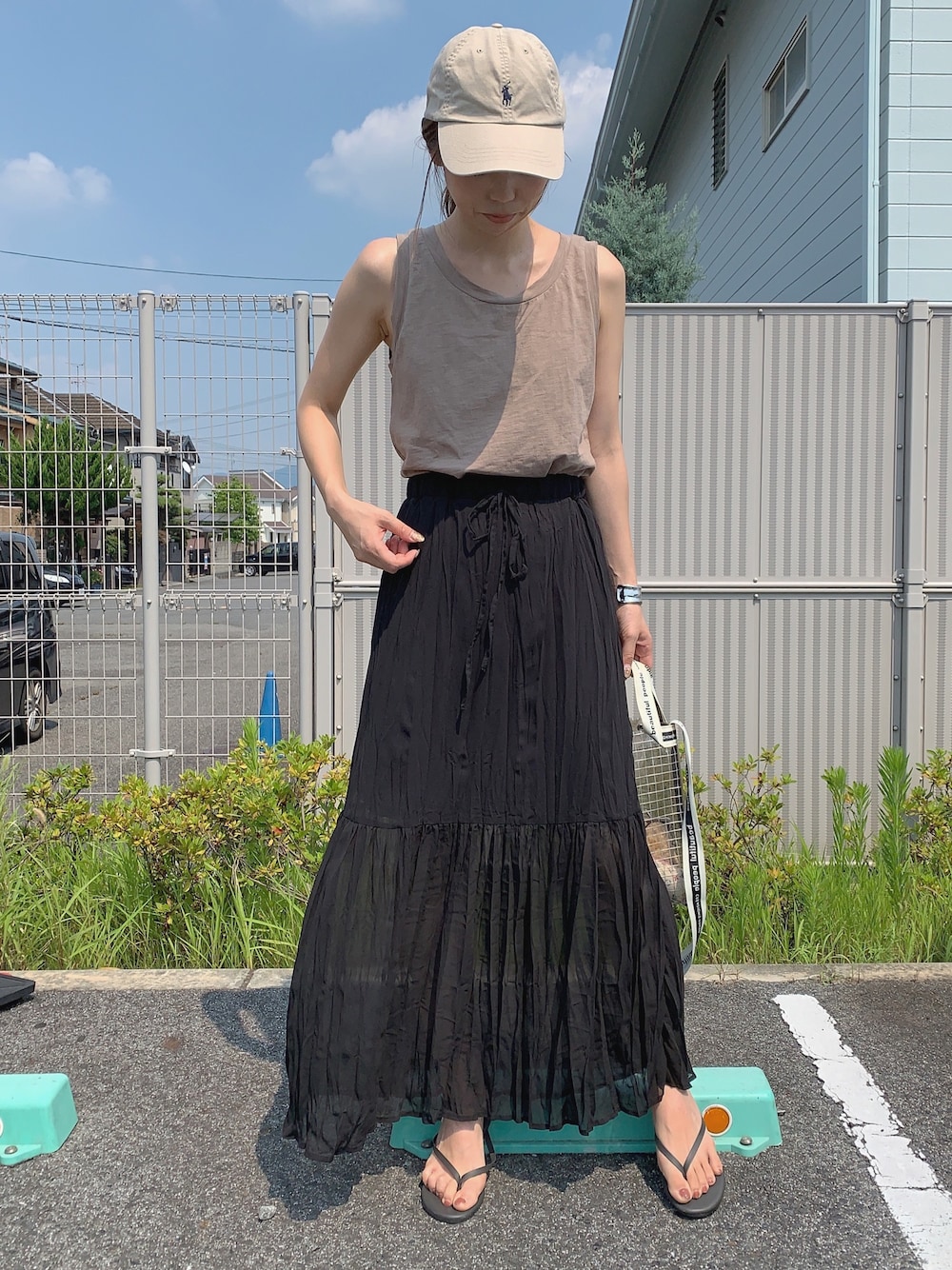 ブラック系のスカート、ブラック系のショルダーバッグ、ブラック系のサンダルを着用したレディースの夏コーディネートの1枚目の写真