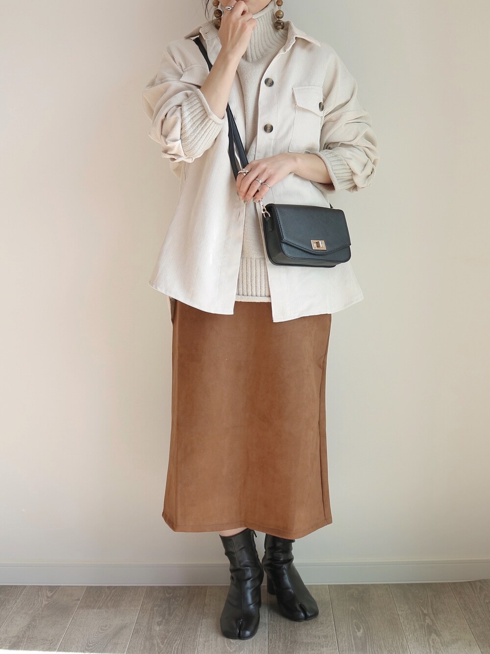 ブラウン系のスカート、ホワイト系のシャツ/ブラウス、ベージュ系のニット/セーターを着用したレディースの秋コーディネートの1枚目の写真