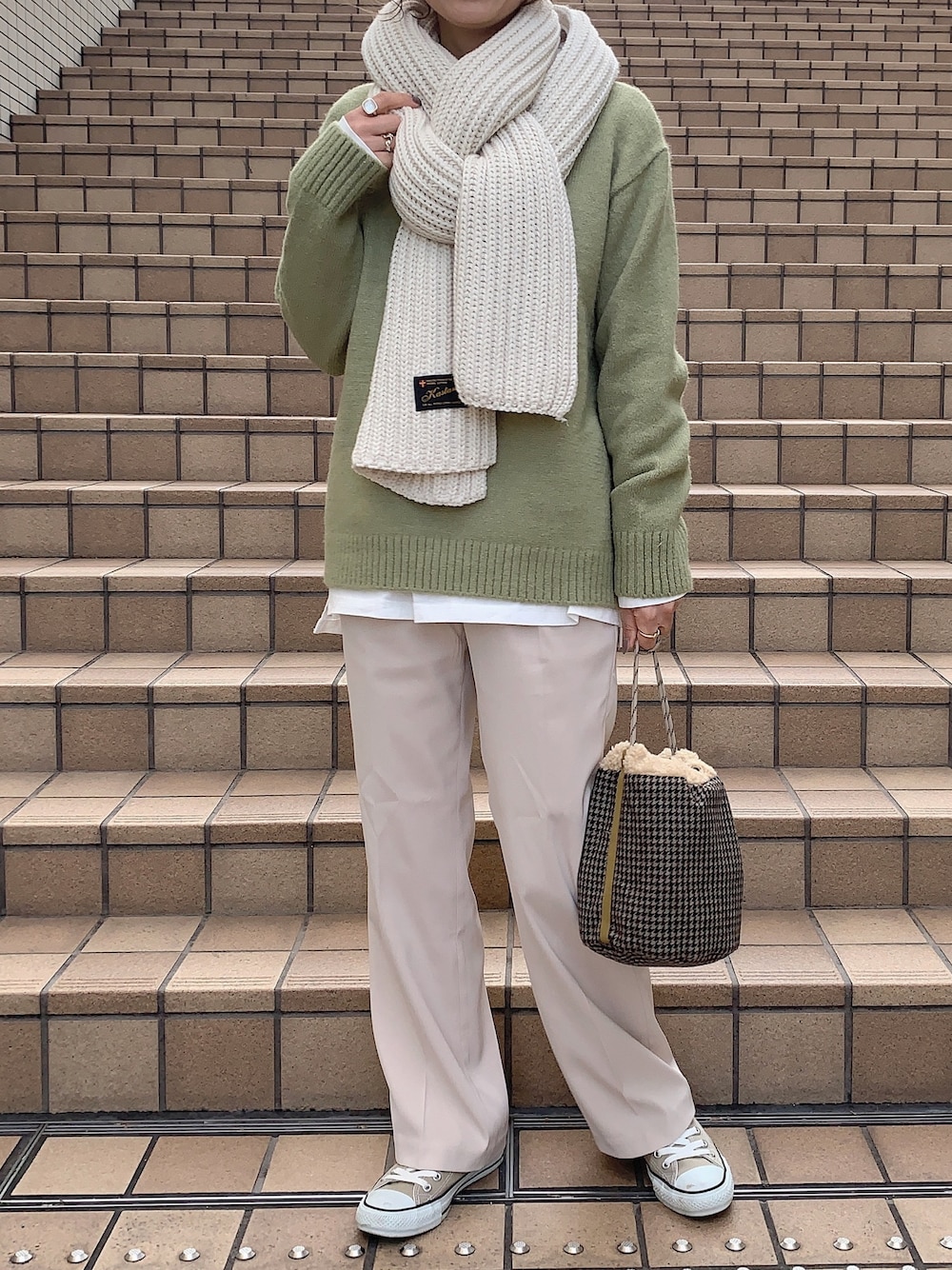グリーン系のニット/セーター、ホワイト系のその他パンツ、イエロー系のハンドバッグを着用したレディースの冬コーディネートの1枚目の写真