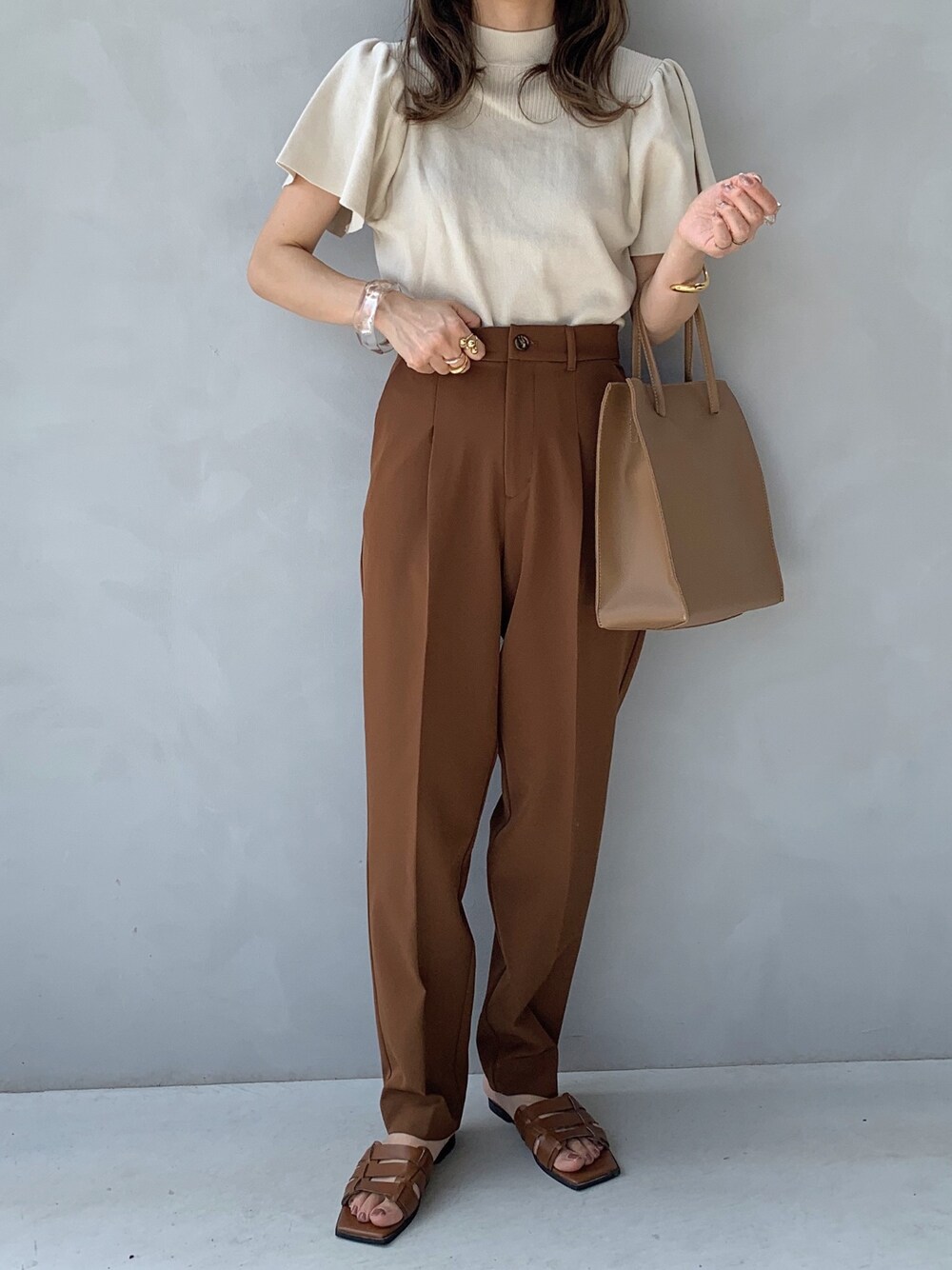 ベージュ系のニット/セーター、ブラウン系のその他パンツ、ベージュ系のトートバッグを着用したレディースの夏コーディネートの1枚目の写真