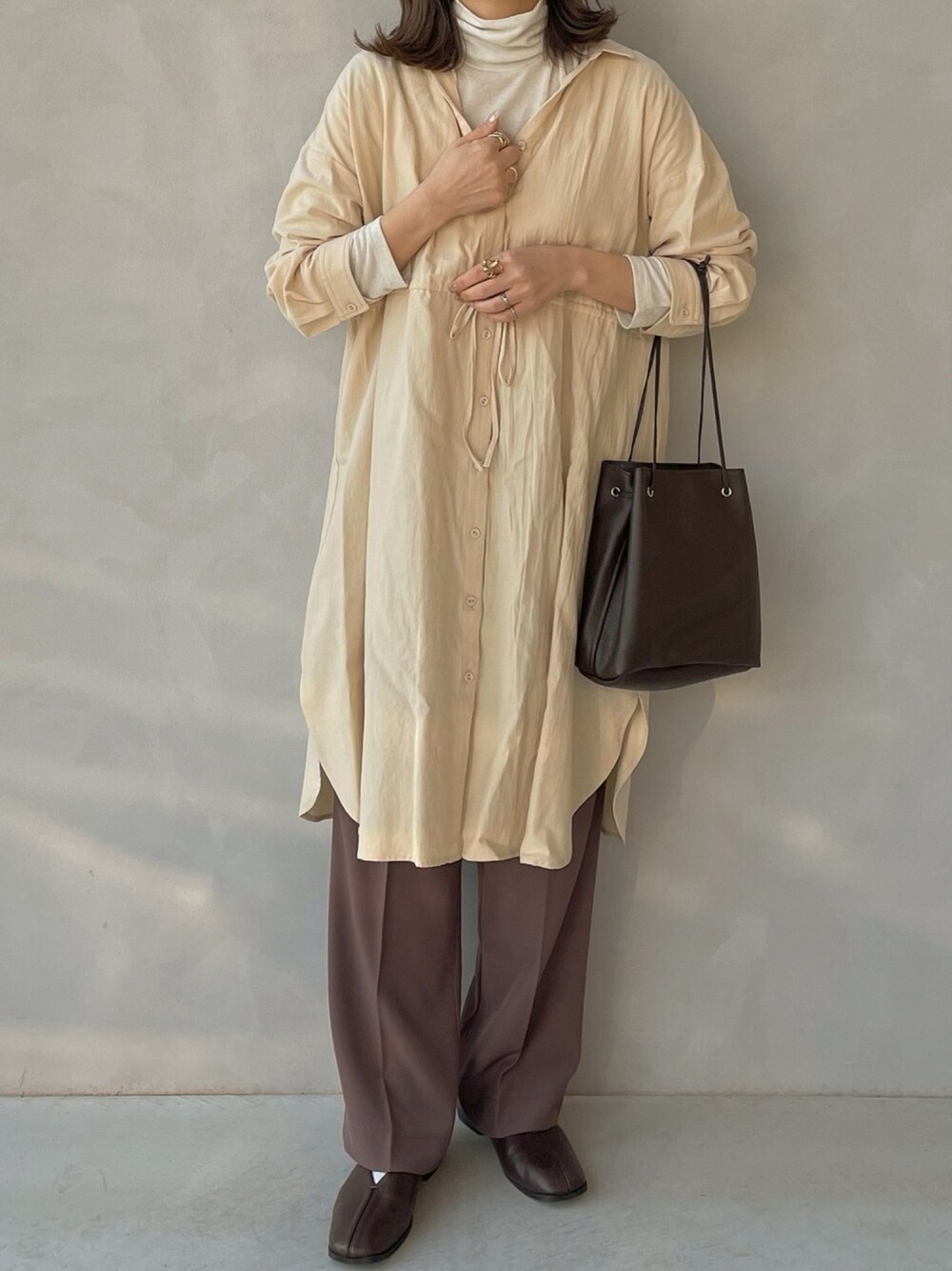 ベージュ系のシャツワンピース、ブラウン系のその他パンツ、ブラウン系のハンドバッグを着用したレディースの冬コーディネートの1枚目の写真