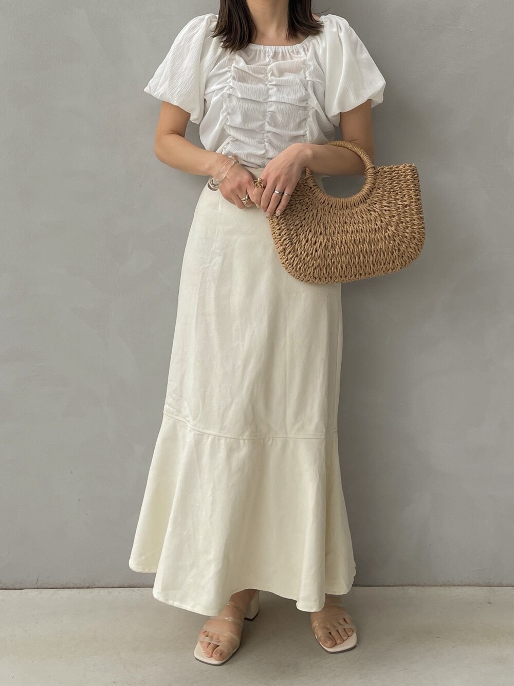 ホワイト系のシャツ/ブラウス、ホワイト系のスカート、ベージュ系のかごバッグを着用したレディースの春コーディネートの1枚目の写真
