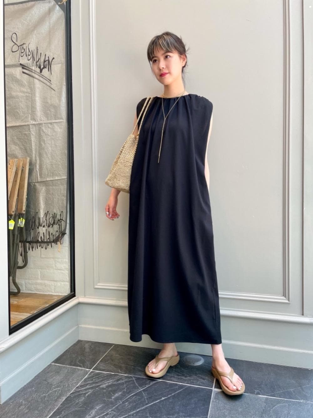 ベージュ系のタンクトップ、ゴールド系のトートバッグ、ブラック系のワンピースを着用したレディースの夏コーディネートの1枚目の写真