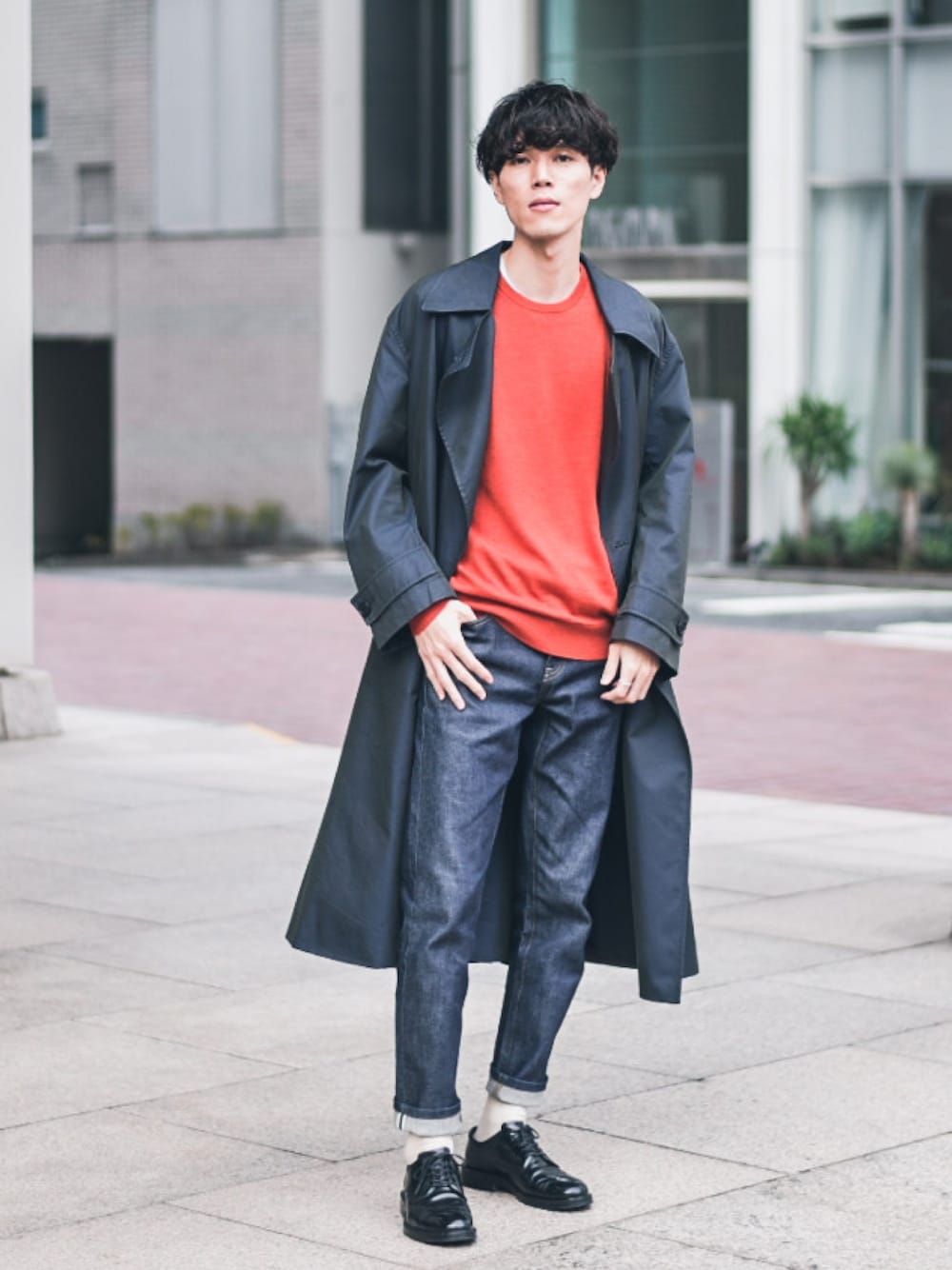 ブルー系のトレンチコート、オレンジ系のニット/セーター、ブルー系のデニムパンツを着用したメンズの秋コーディネートの1枚目の写真