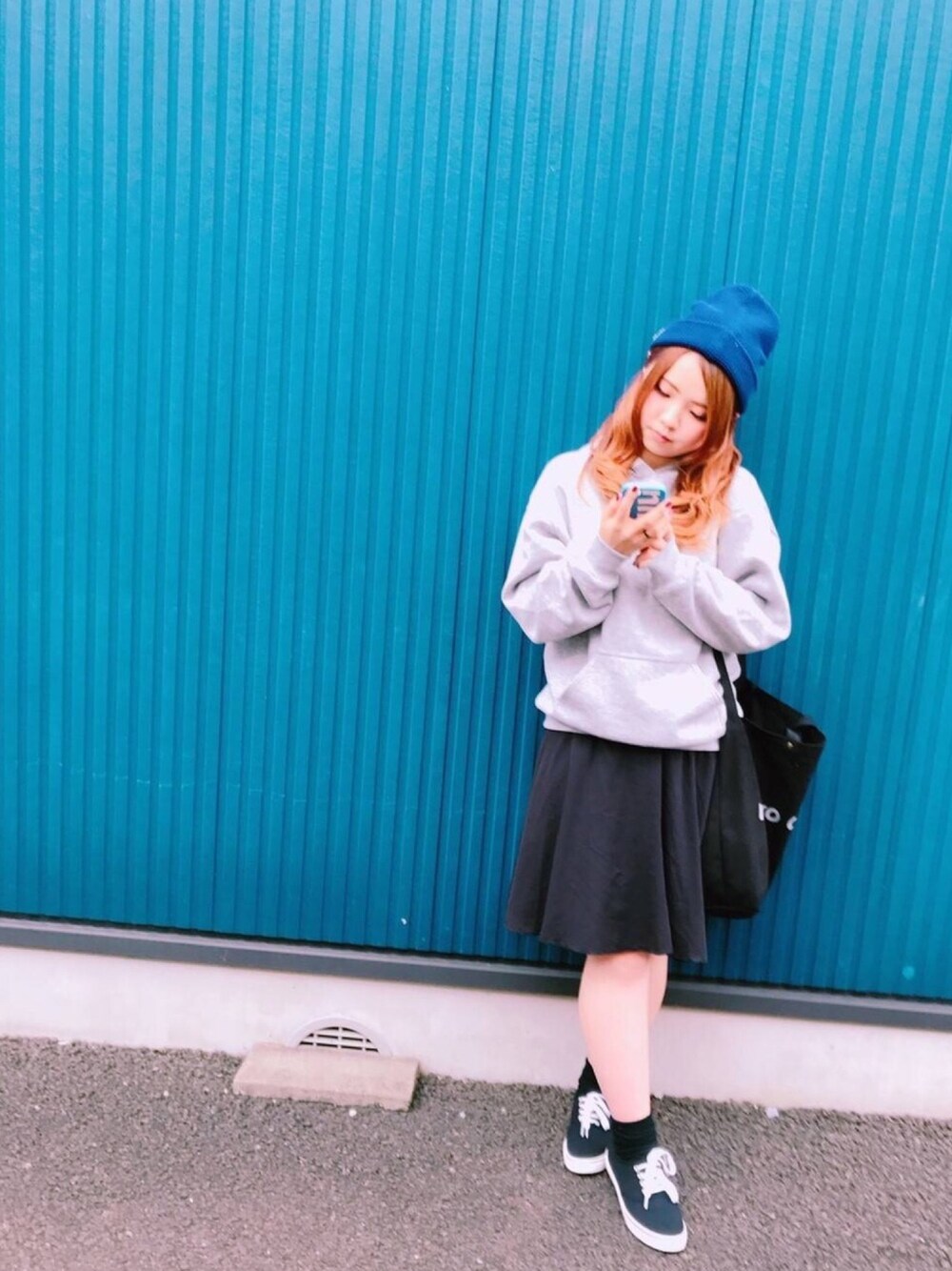 グレー系のトップス、ブラック系のスカート、ブラック系のトートバッグを着用したレディースの秋コーディネートの1枚目の写真