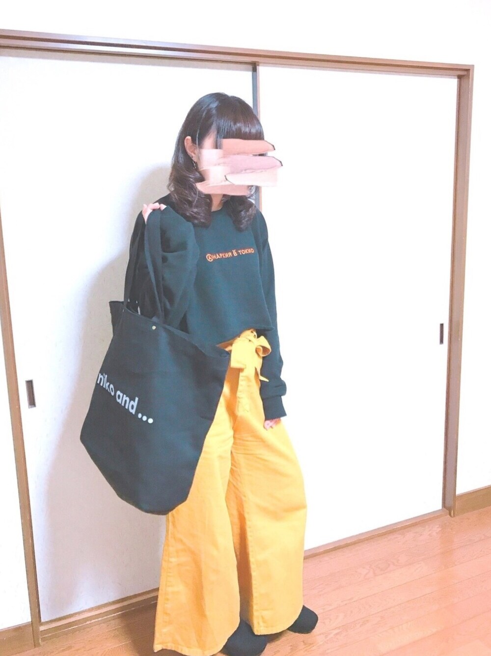 ブラック系のスウェット、イエロー系のパンツ、ブラック系のトートバッグを着用したレディースの春コーディネートの1枚目の写真