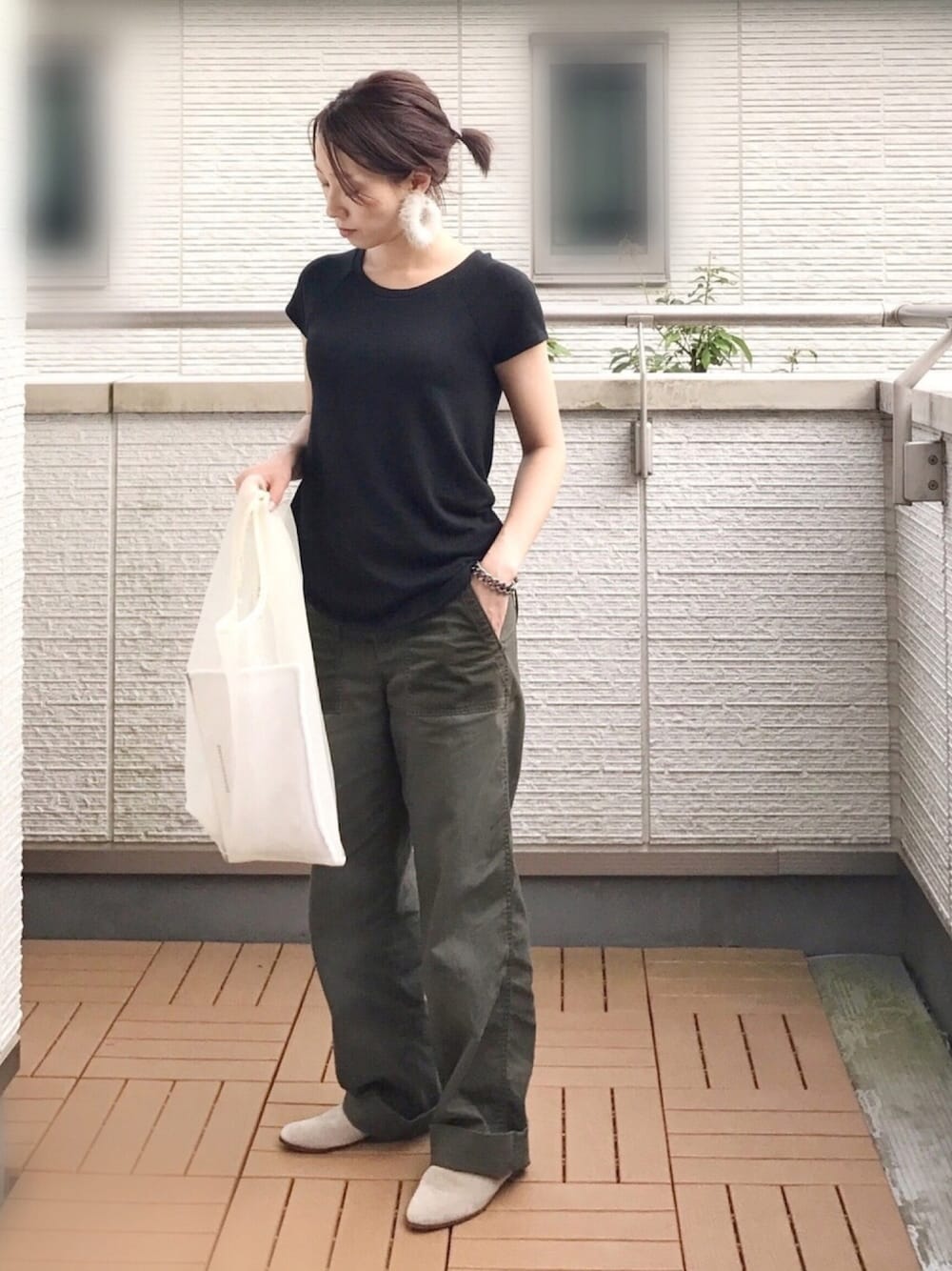 ブラック系のTシャツ/カットソー、グリーン系のチノパンツ、ベージュ系のサンダルを着用したレディースの秋コーディネートの1枚目の写真