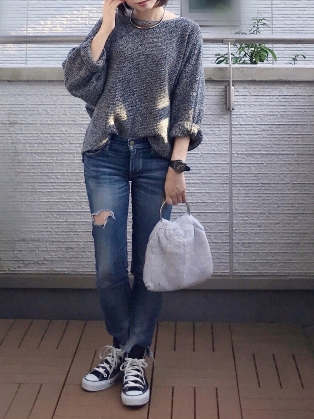 グレー系のニット/セーター、ブルー系のデニムパンツ、グレー系のショルダーバッグを着用したレディースの秋コーディネートの1枚目の写真