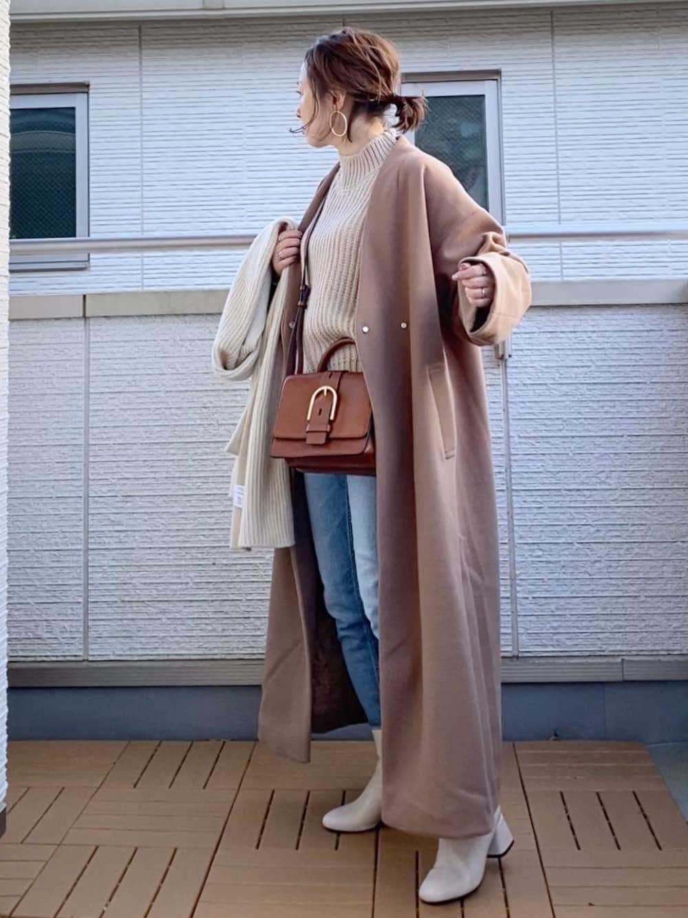 ブラウン系のノーカラーコート、ベージュ系のニット/セーター、ブラウン系のショルダーバッグを着用したレディースの冬コーディネートの1枚目の写真