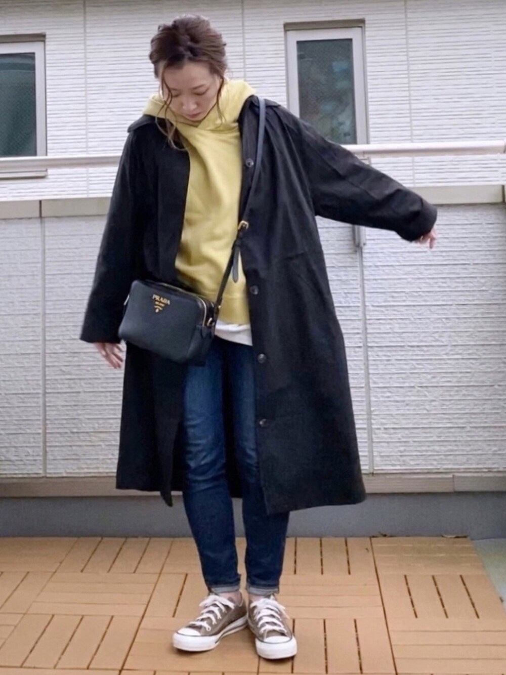 ブラック系のその他アウター、イエロー系のパーカー、ブルー系のデニムパンツを着用したレディースの春コーディネートの1枚目の写真