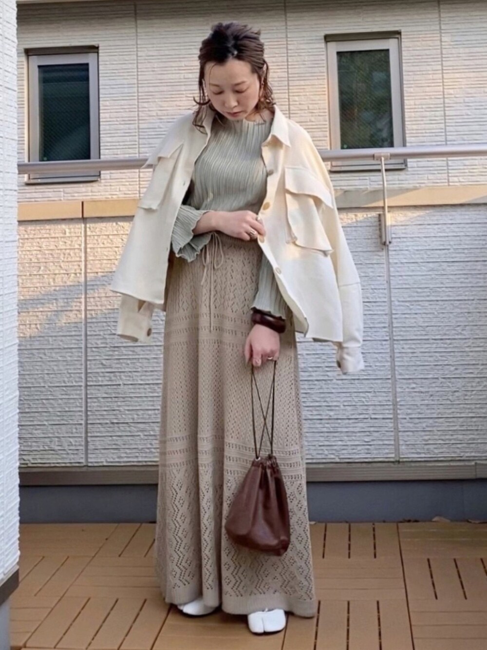 ホワイト系のその他アウター、グリーン系のTシャツ/カットソー、ベージュ系のスカートを着用したレディースの春コーディネートの1枚目の写真