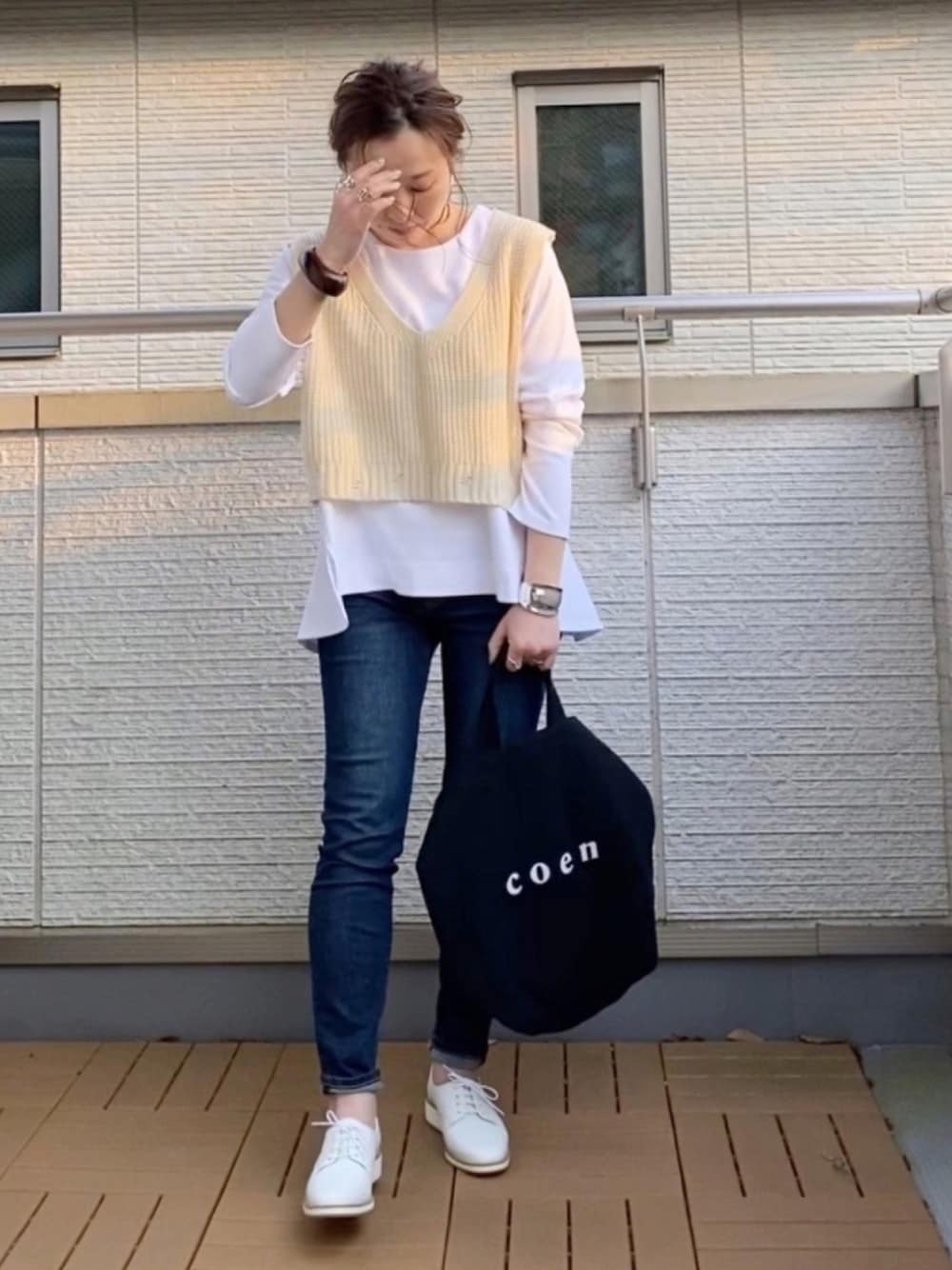 ホワイト系のTシャツ/カットソー、ホワイト系のベスト、ブルー系のデニムパンツを着用したレディースの春コーディネートの1枚目の写真