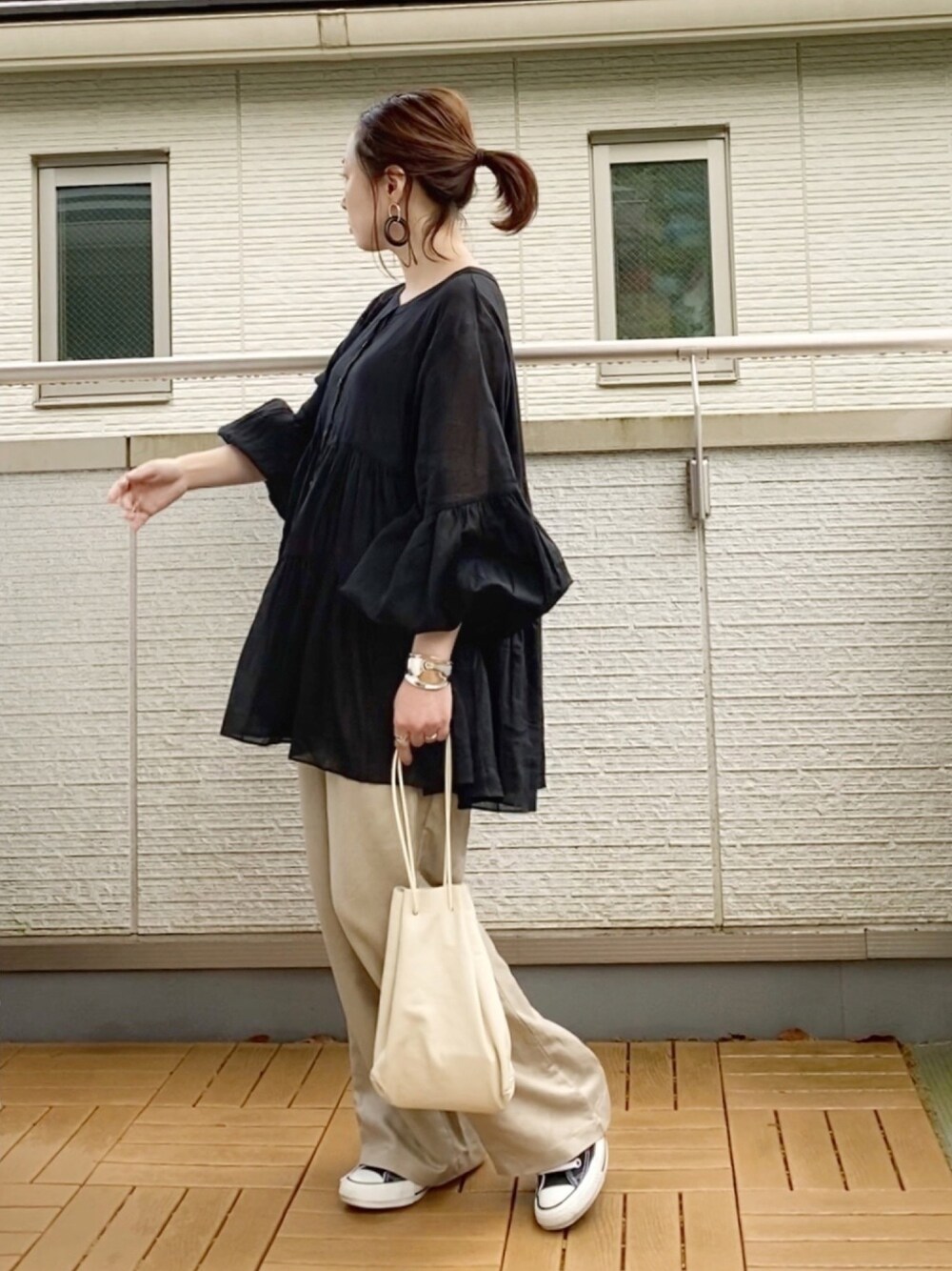 ブラック系のシャツ/ブラウス、ベージュ系のその他パンツ、ホワイト系のショルダーバッグを着用したレディースの春コーディネートの1枚目の写真