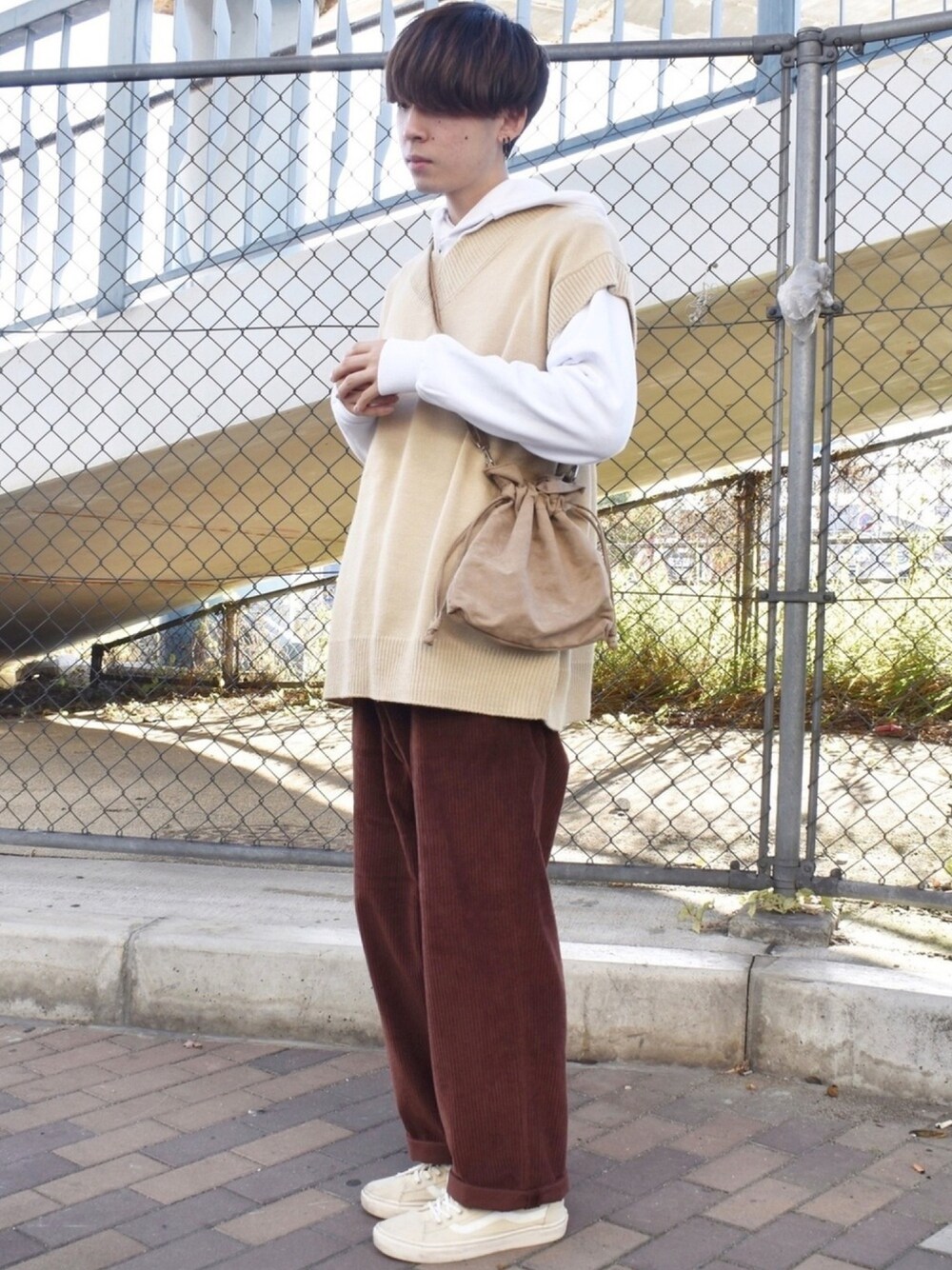 ベージュ系のベスト、ホワイト系のパーカー、ベージュ系のショルダーバッグを着用したメンズの秋コーディネートの1枚目の写真