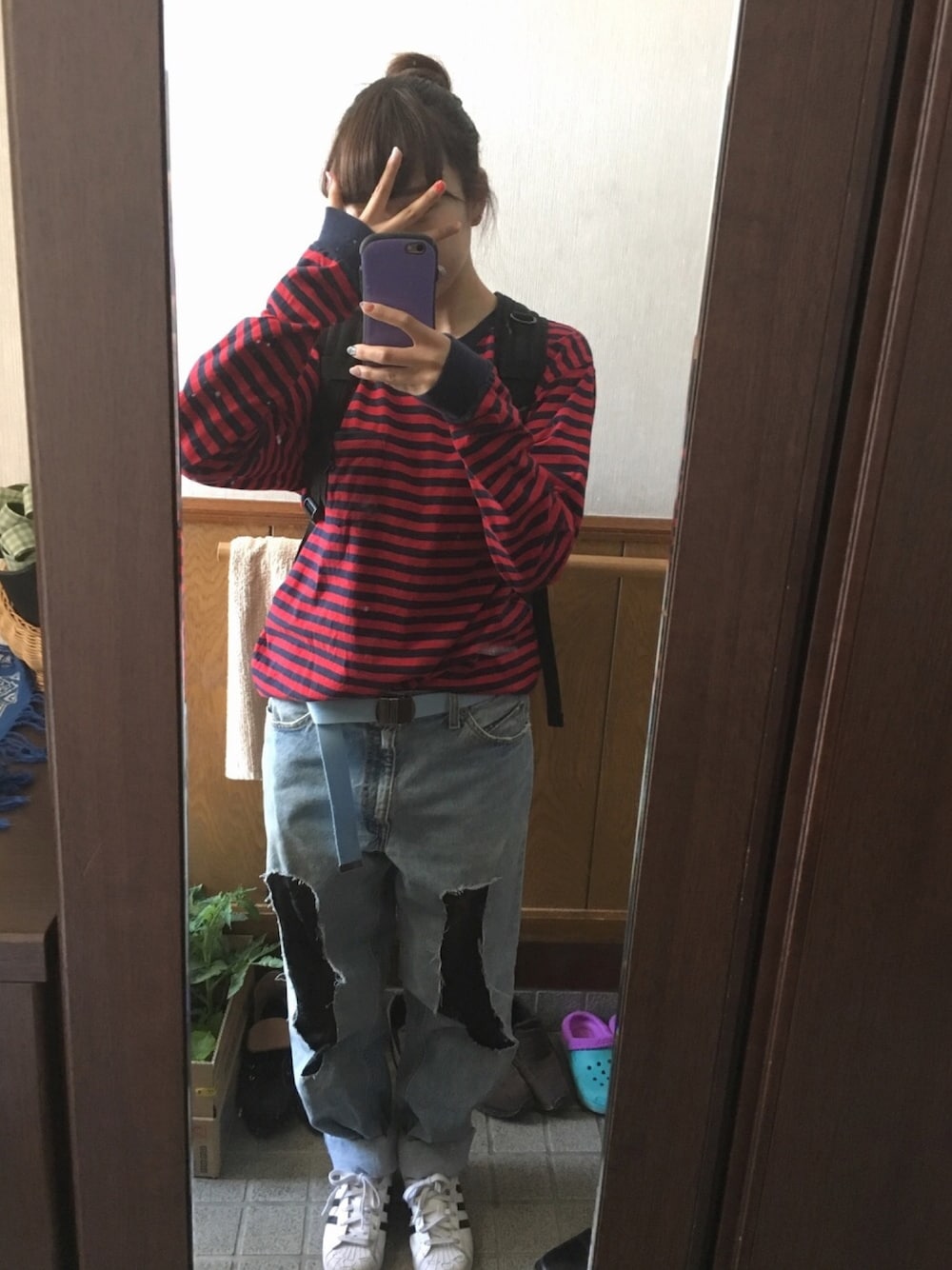 レッド系のTシャツ/カットソー、ブルー系のデニムパンツ、ホワイト系のスニーカーを着用したレディースの春コーディネートの1枚目の写真