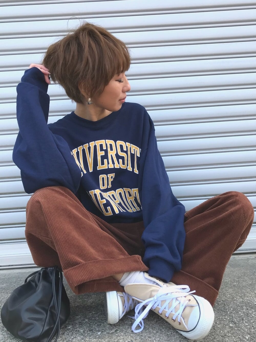 ブルー系のスウェット、ブラウン系のパンツ、ブラック系のショルダーバッグを着用したレディースの冬コーディネートの1枚目の写真