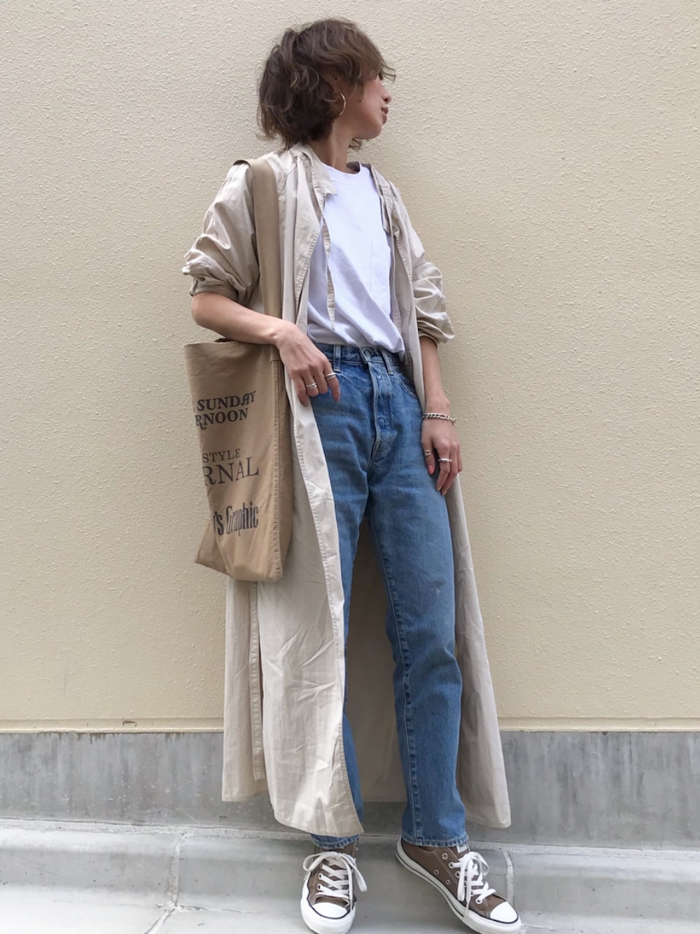 ベージュ系のトレンチコート、ホワイト系のTシャツ/カットソー、ベージュ系のトートバッグを着用したレディースの春コーディネートの1枚目の写真