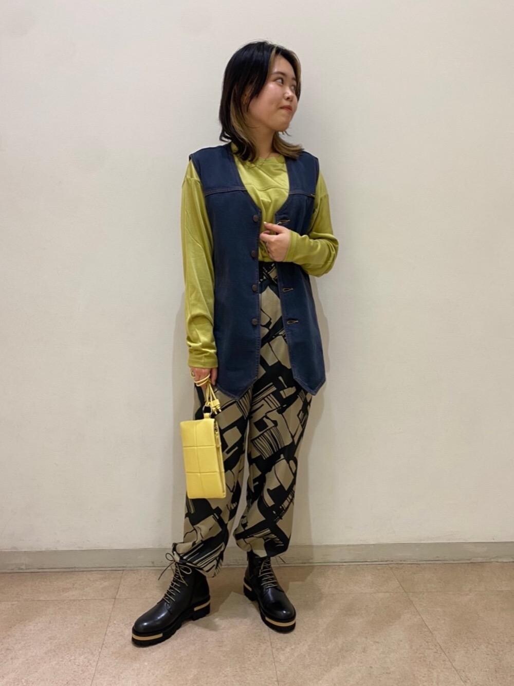 ブラック系のベスト、ブラック系のブーツ、イエロー系のショルダーバッグを着用したレディースの秋コーディネートの1枚目の写真