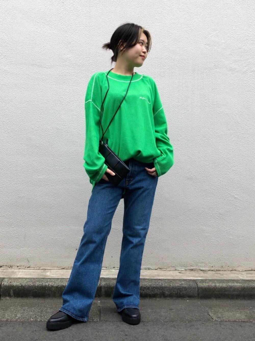 ブルー系のデニムパンツ、ブラック系のショルダーバッグ、グリーン系のTシャツ/カットソーを着用したレディースの秋コーディネートの1枚目の写真