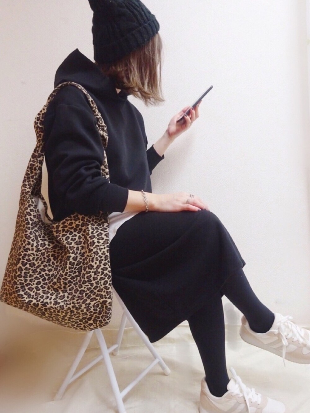 ベージュ系のスニーカー、ブラック系のスカート、ベージュ系のバッグを着用したレディースの冬コーディネートの1枚目の写真