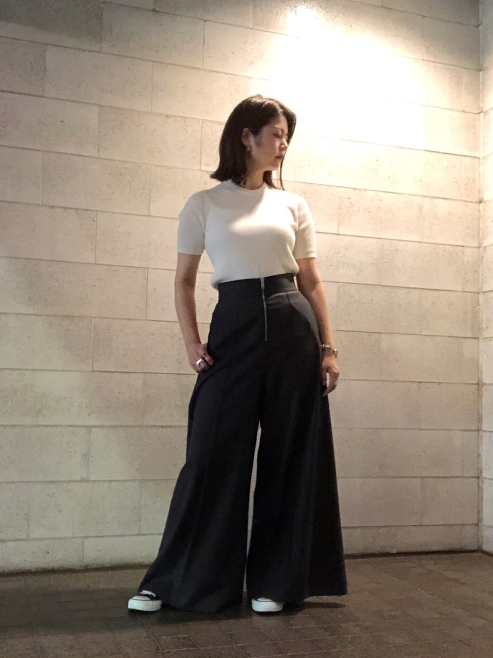 グレー系のパンツ、ブラック系のスニーカー、ホワイト系のニット/セーターを着用したレディースの夏コーディネートの1枚目の写真