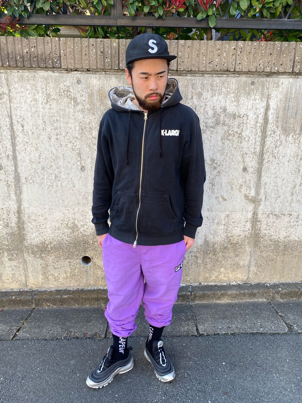 ブラック系のパーカー、パープル系のパンツ、シルバー系のスニーカーを着用したメンズの春コーディネートの1枚目の写真