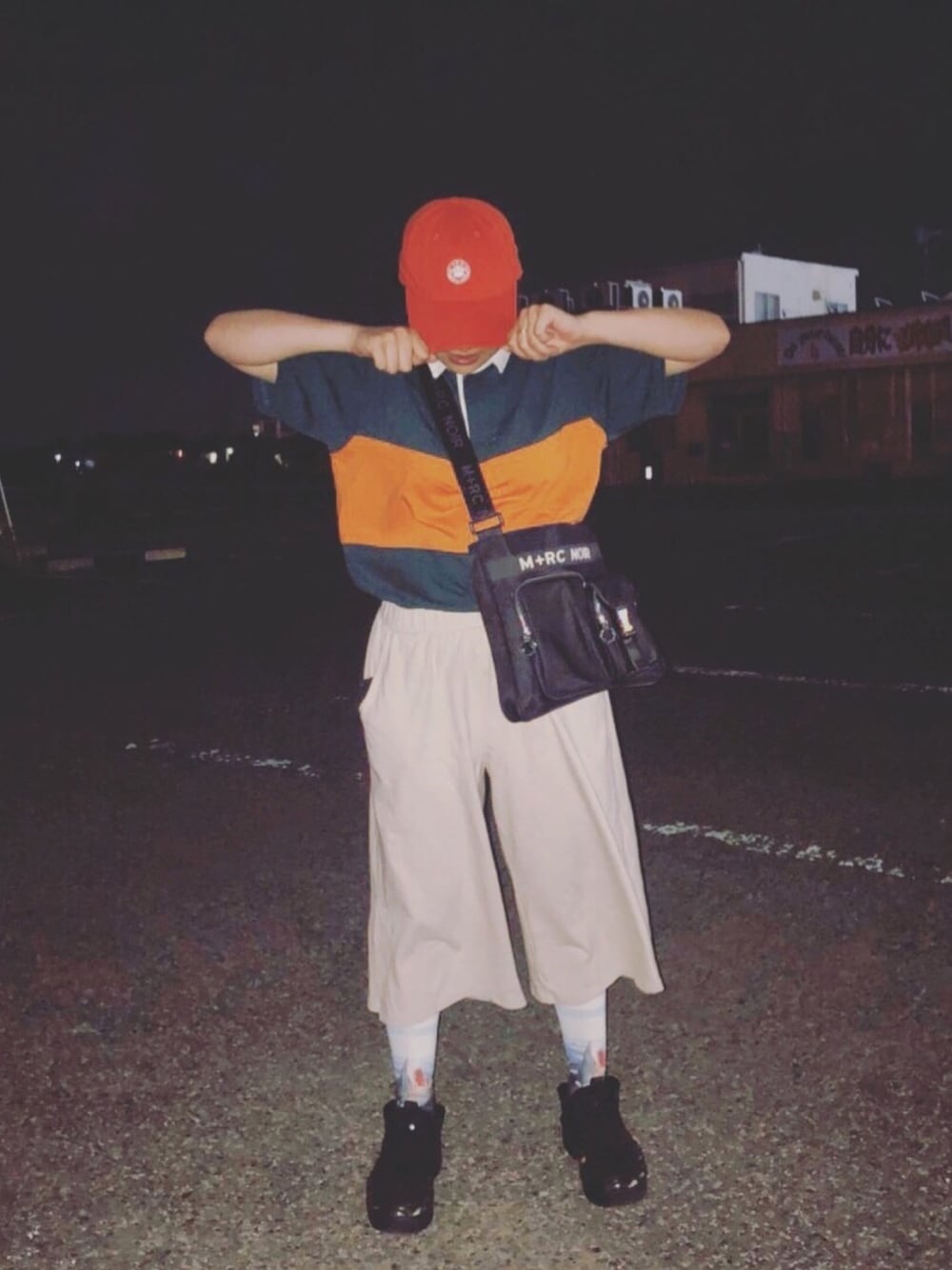 グリーン系のポロシャツ、ブラック系のメッセンジャーバッグ、ベージュ系のパンツを着用したレディースの夏コーディネートの1枚目の写真