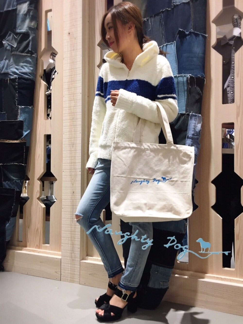 ホワイト系のトートバッグ、ブルー系のデニムパンツ、ホワイト系のパーカーを着用したレディースの秋コーディネートの1枚目の写真