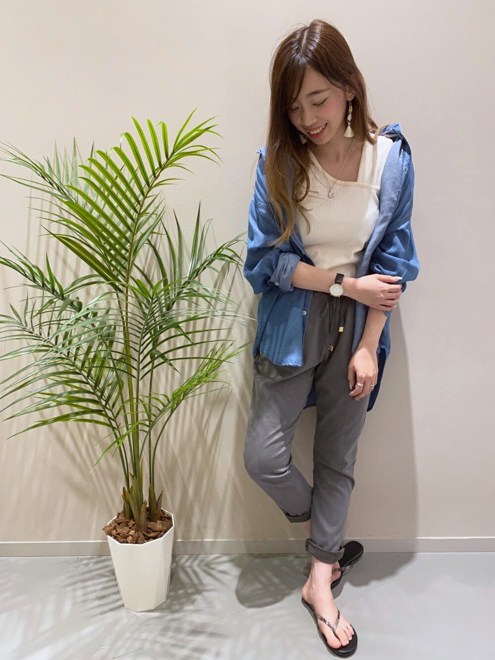 グレー系のスラックス、ブラック系のサンダル、ホワイト系のタンクトップを着用したレディースの春コーディネートの1枚目の写真