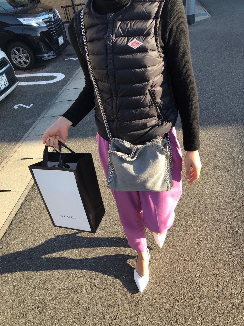 グレー系のショルダーバッグ、ブラック系のダウンベスト、ピンク系のその他パンツを着用したレディースの冬コーディネートの1枚目の写真