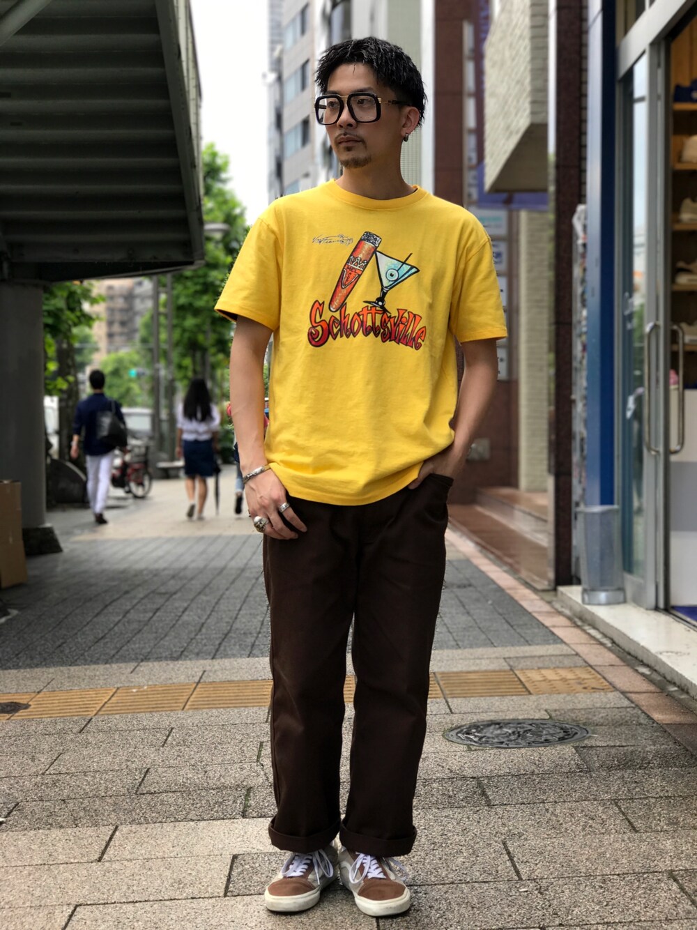 イエロー系のTシャツ/カットソー、ブラウン系のチノパンツ、ブラウン系のスニーカーを着用したメンズの夏コーディネートの1枚目の写真